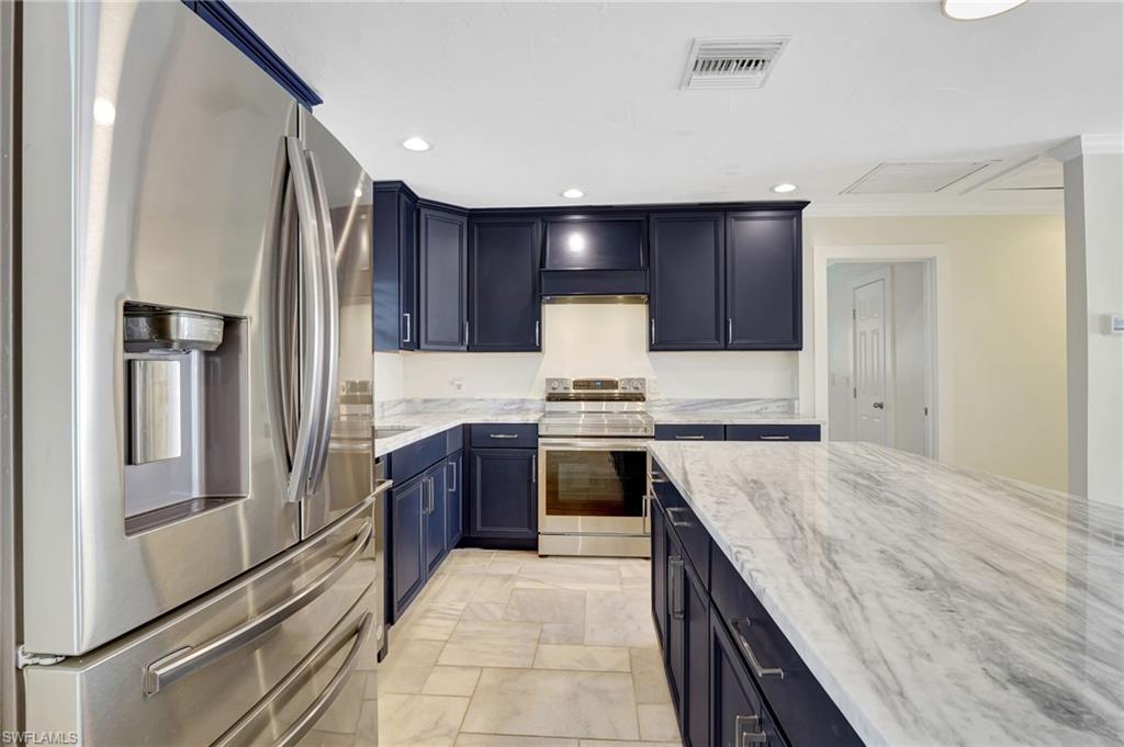 112 Capri Boulevard Naples, FL 34113 - Photo 9 of 39 a large kitchen with granite countertop a refrigerator and a stove top oven
