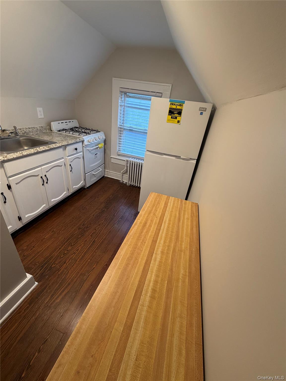 196 Depew Avenue, Unit 3 Nyack, NY 10960 - Photo 8 of 15 Kitchen with white appliances, lofted ceiling, dark wood-style floors, white cabinets, and radiator heating unit