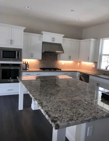 a kitchen with stainless steel appliances granite countertop a sink a stove and a microwave