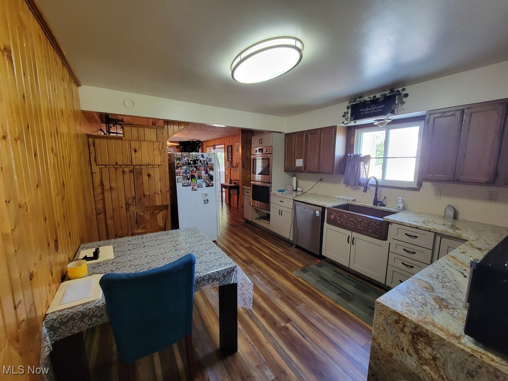 42774 Webster Road Lagrange, OH 44050 - Photo 13 of 37 Kitchen featuring wood walls, dark wood-style flooring, light stone counters, and stainless steel appliances
