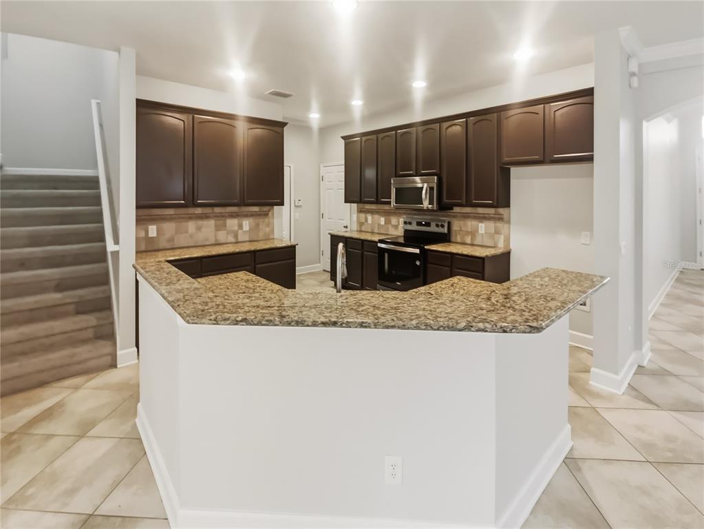 4307 Rustic Pine Place Wesley Chapel, FL 33544 - Photo 2 of 38 a kitchen with granite countertop a sink and stainless steel appliances