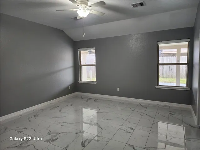 an empty room with windows and chandelier fan