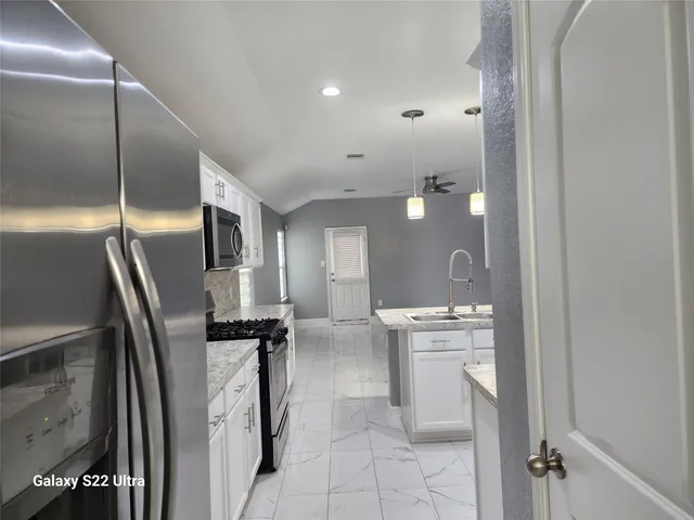 a kitchen with stainless steel appliances granite countertop a refrigerator and a stove