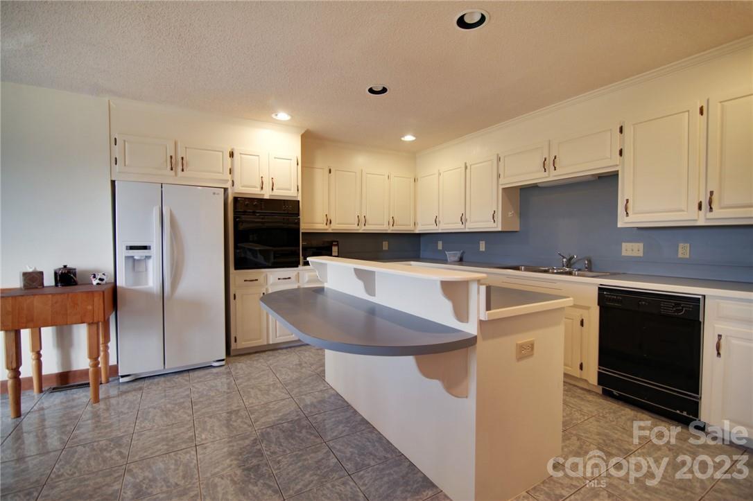 7100 Highway 108 Mill Spring, NC 28756 - Photo 23 of 48 a kitchen with kitchen island granite countertop a stove a sink and a refrigerator