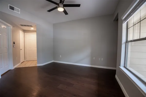an empty room with wooden floor and windows