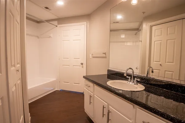 a bathroom with a sink double vanity granite tub shower and a mirror