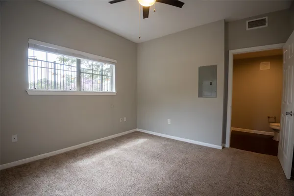en empty room with windows and chandelier fan
