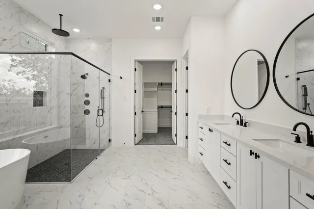 a spacious bathroom with a double vanity sink a mirror a bathtub and shower