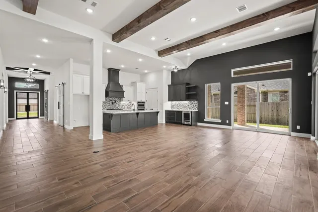 a view of a living room a kitchen with stainless steel appliances granite countertop a stove and a refrigerator