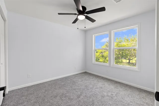 an empty room with windows and ceiling fan
