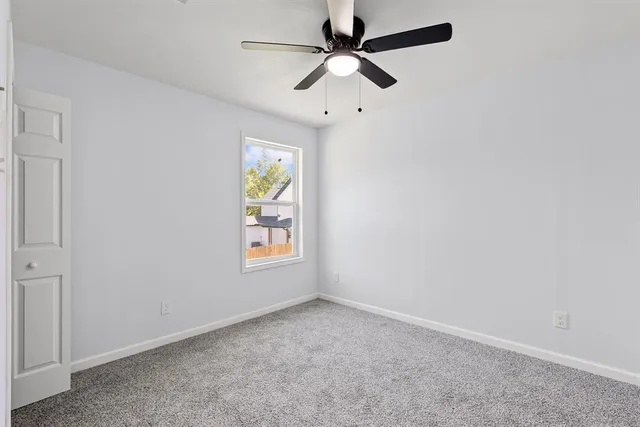 an empty room with window and ceiling fan