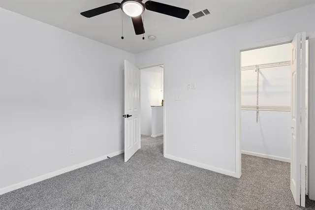 an empty room with closet and a ceiling fan