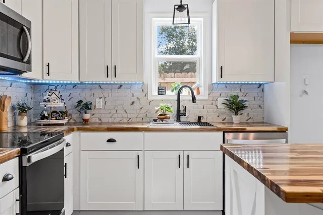 a kitchen with stainless steel appliances white cabinets and a stove top oven