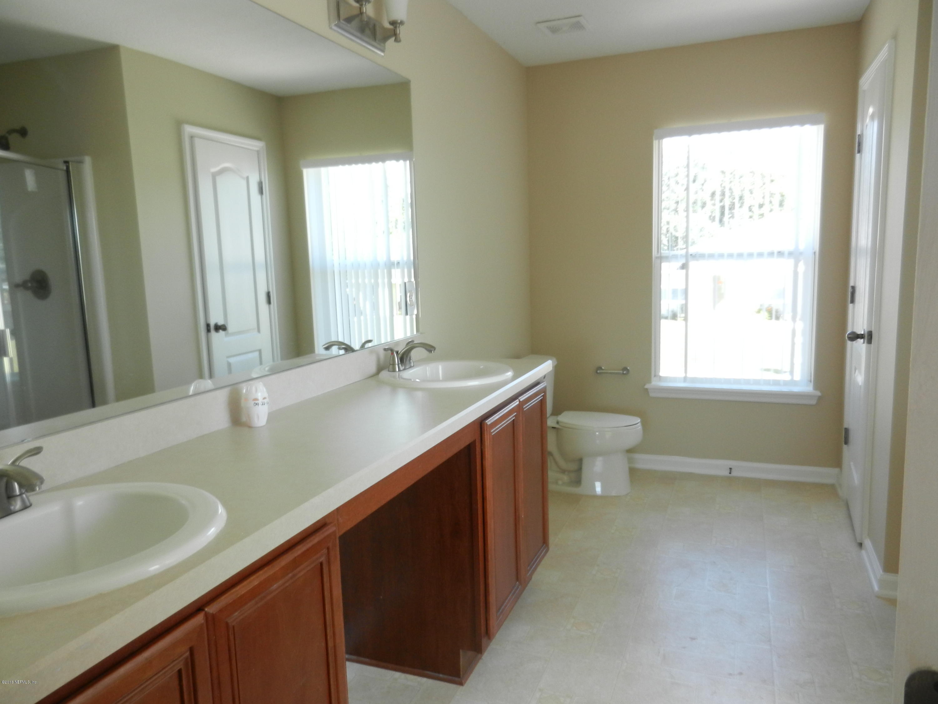 86339 Cartesian Pointe Drive Yulee, FL 32097 - Photo 16 of 21 a bathroom with a double vanity sink toilet and a mirror