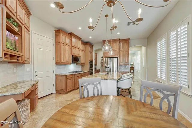 a large white kitchen with stainless steel appliances kitchen island granite countertop a large island in the center