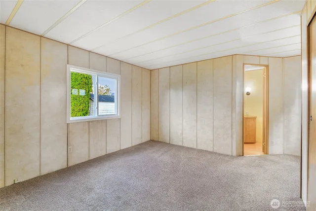a view of an empty room with window and a bathroom