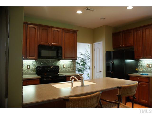 3413 Cathedral Bell Road Raleigh, NC 27614 - Photo 5 of 22 a kitchen with kitchen island a stove a sink a refrigerator with a dining table and chairs