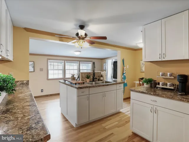 a kitchen that has a lot of white cabinets and stainless steel appliances