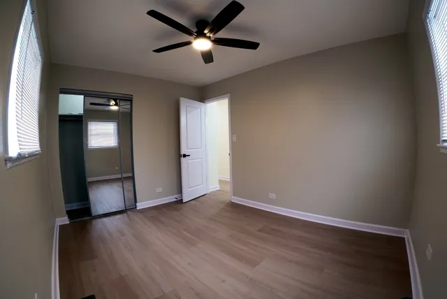 an empty room with wooden floor and a ceiling fan