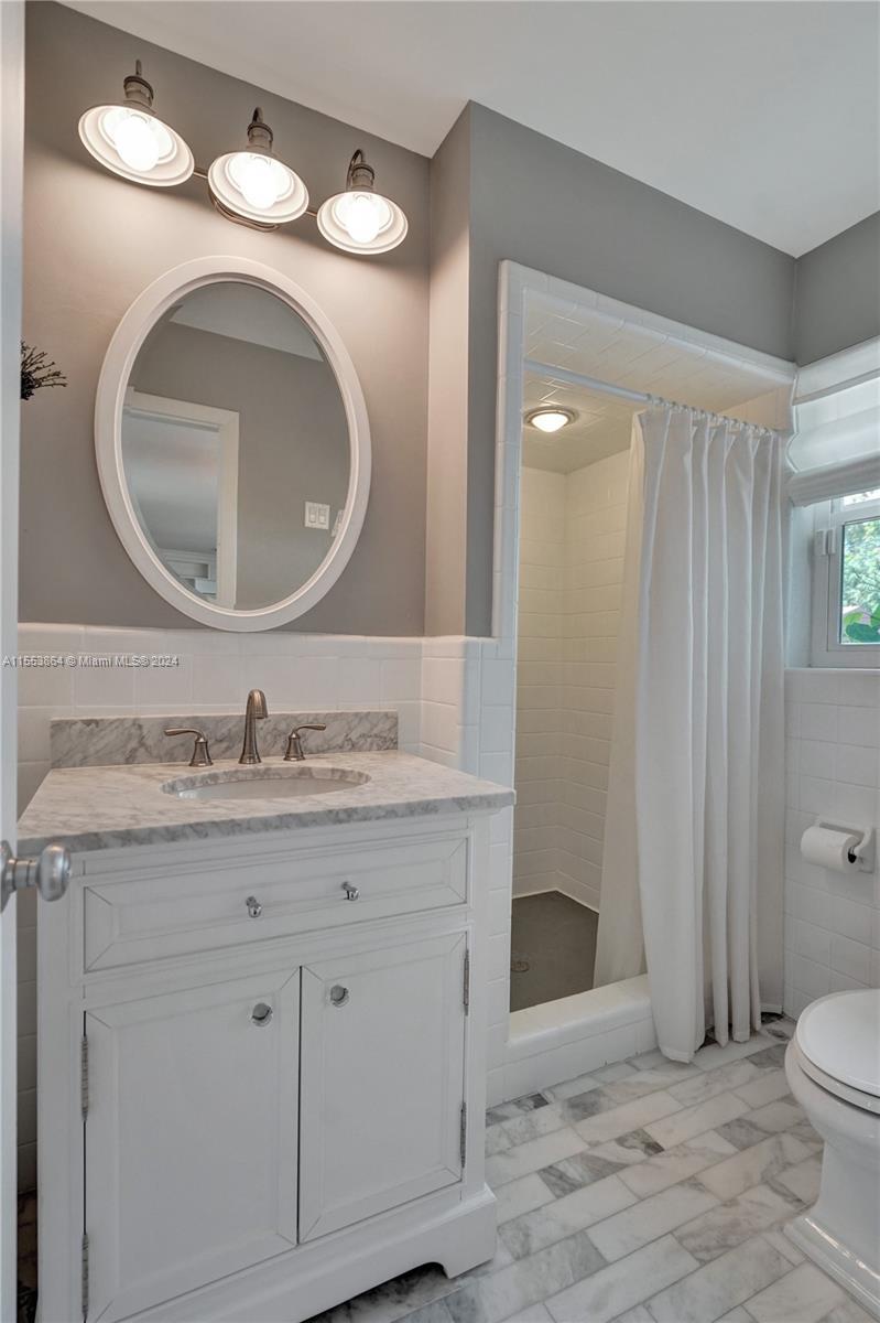 3445 Fillmore Street Hollywood, FL 33021 - Photo 29 of 76 a bathroom with a granite countertop toilet a sink and a mirror