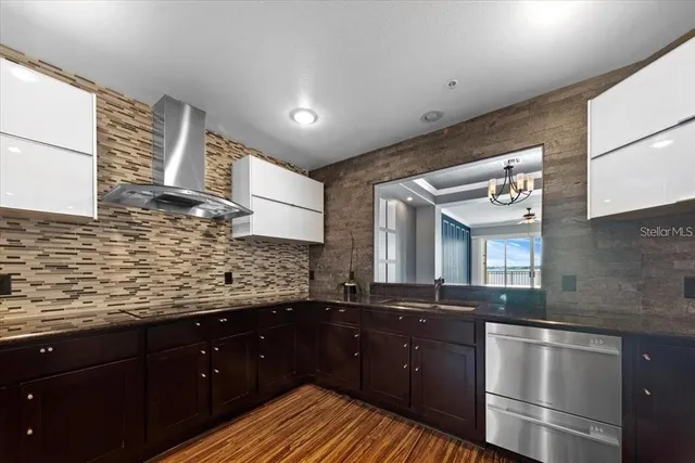 a kitchen with stainless steel appliances granite countertop a sink and wooden floor