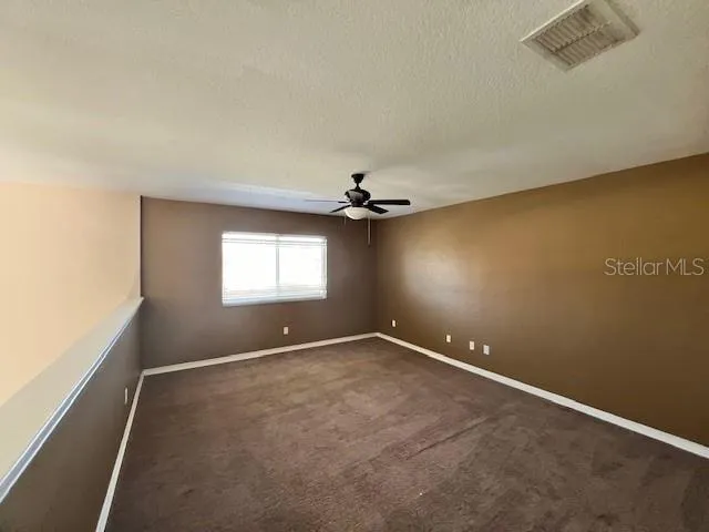 an empty room with a window and a fan