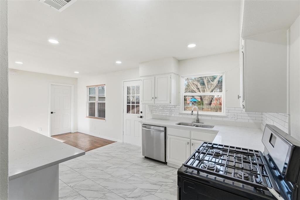 10833 Ruth Ann Drive Dallas, TX 75228 - Photo 7 of 17 a kitchen with stainless steel appliances a sink a stove a refrigerator and white cabinets