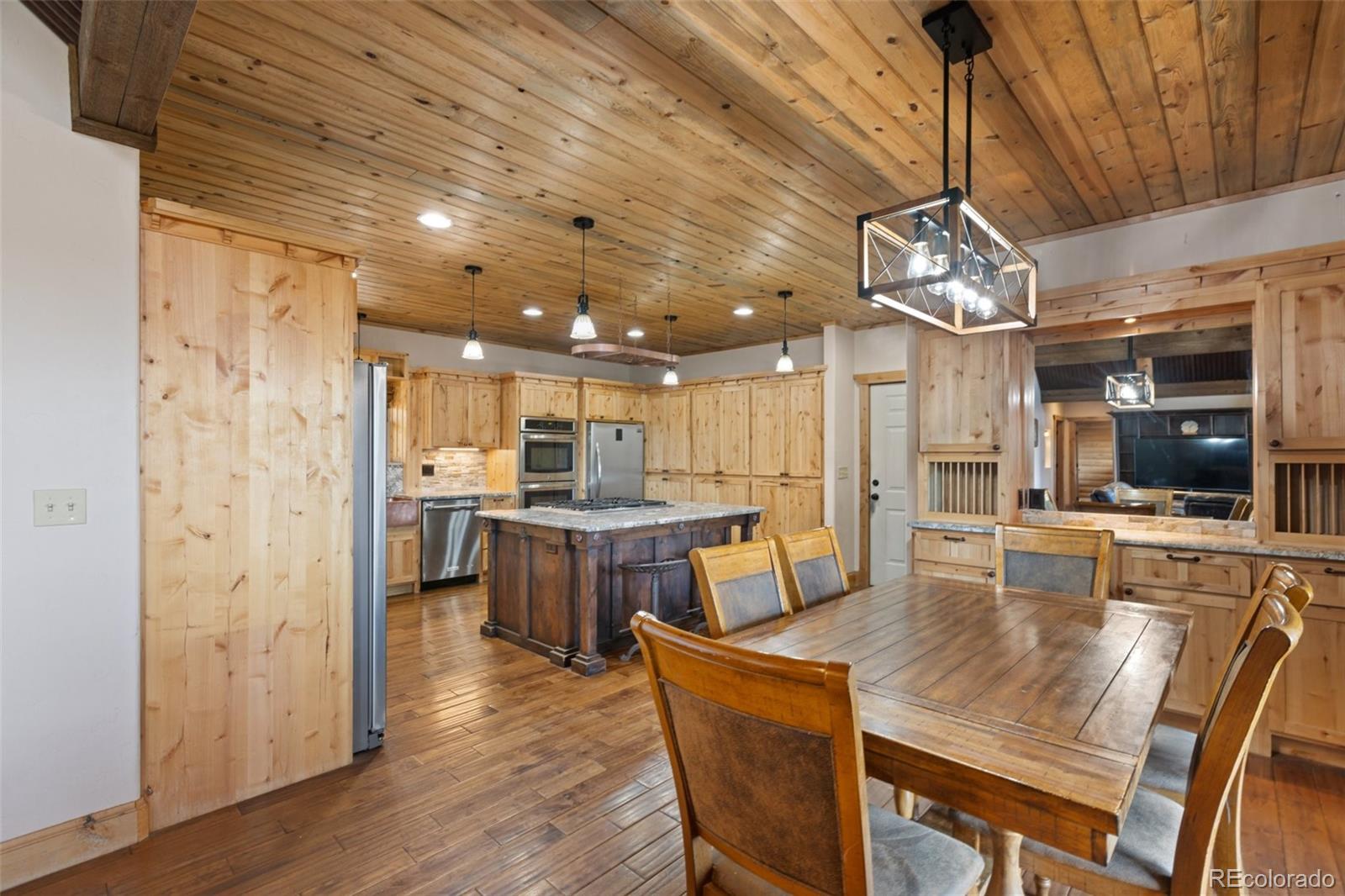 111 Blue Spruce Road Divide, CO 80814 - Photo 21 of 46 a dining room with stainless steel appliances kitchen island granite countertop a table chairs and a chandelier
