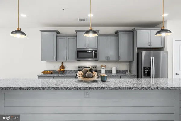 a kitchen with granite countertop a sink cabinets and stainless steel appliances