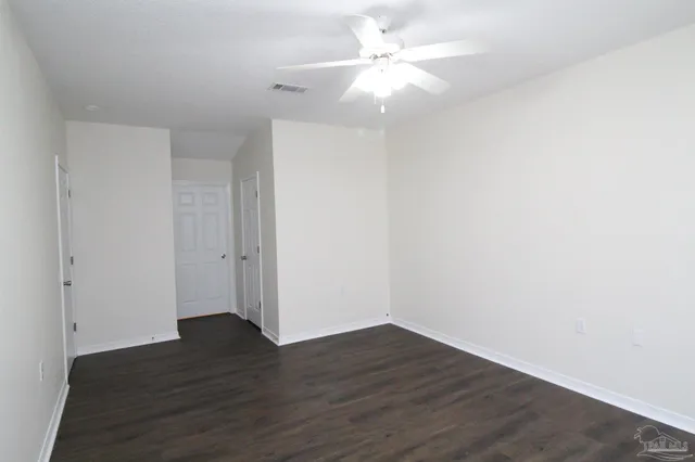 an empty room with wooden floor and fan