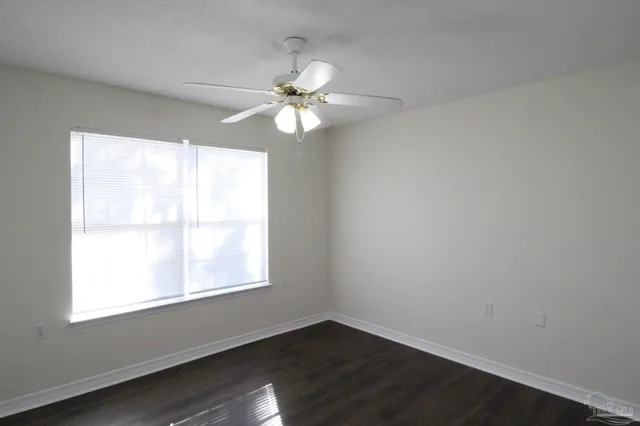 an empty room with windows and fan