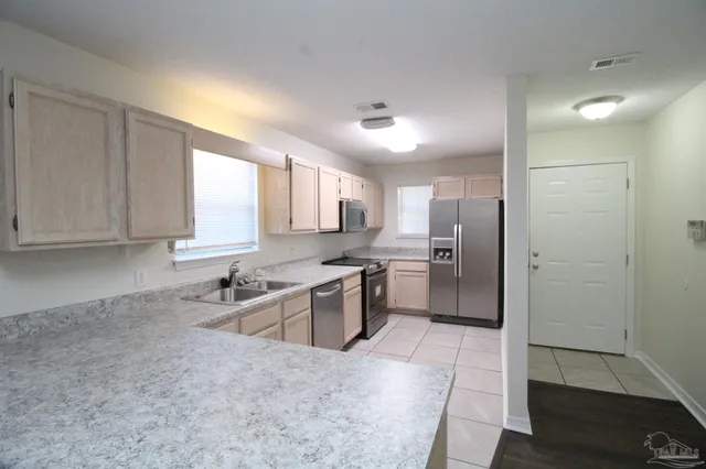 a kitchen with a sink cabinets stainless steel appliances and a window
