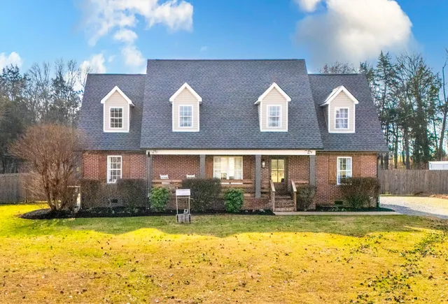 a front view of house with yard and trees in the background