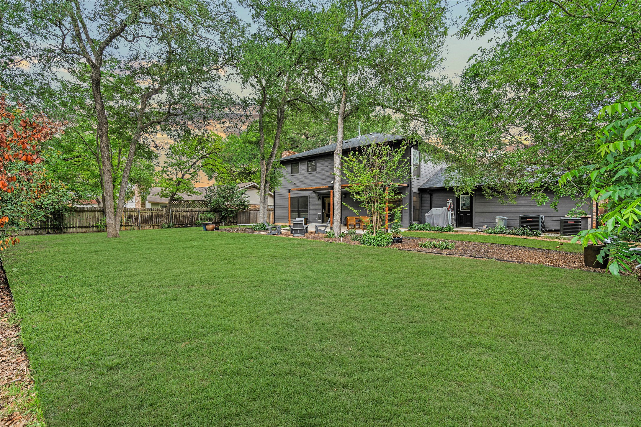 7107 Greenock Street Austin, TX 78749 - Photo 2 of 40 The property features a spacious lawn with mature trees and a dark-colored exterior