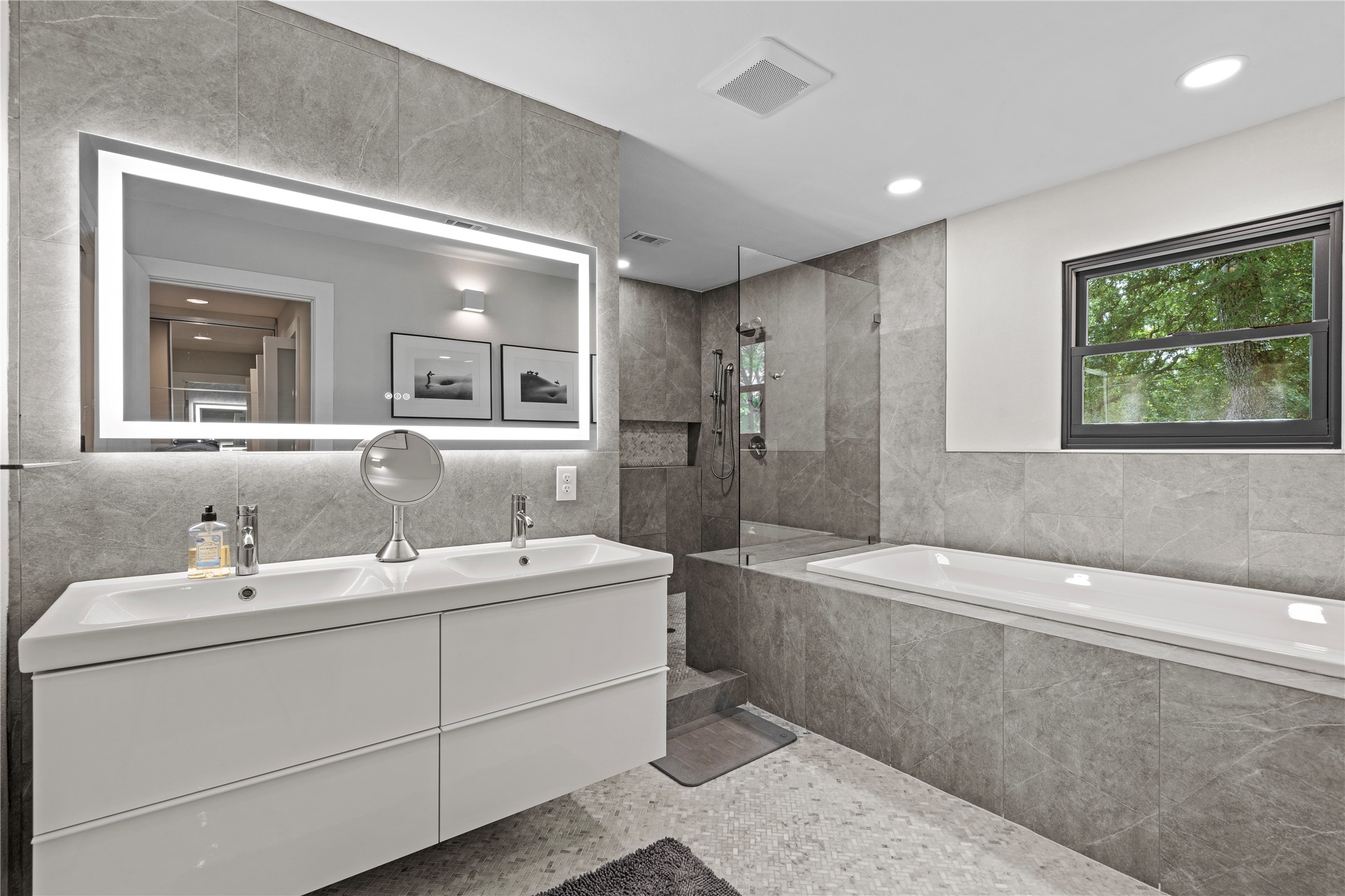 7107 Greenock Street Austin, TX 78749 - Photo 22 of 40 The bathroom features a modern double vanity with an illuminated mirror, a spacious bathtub, and a separate shower area with a glass partition