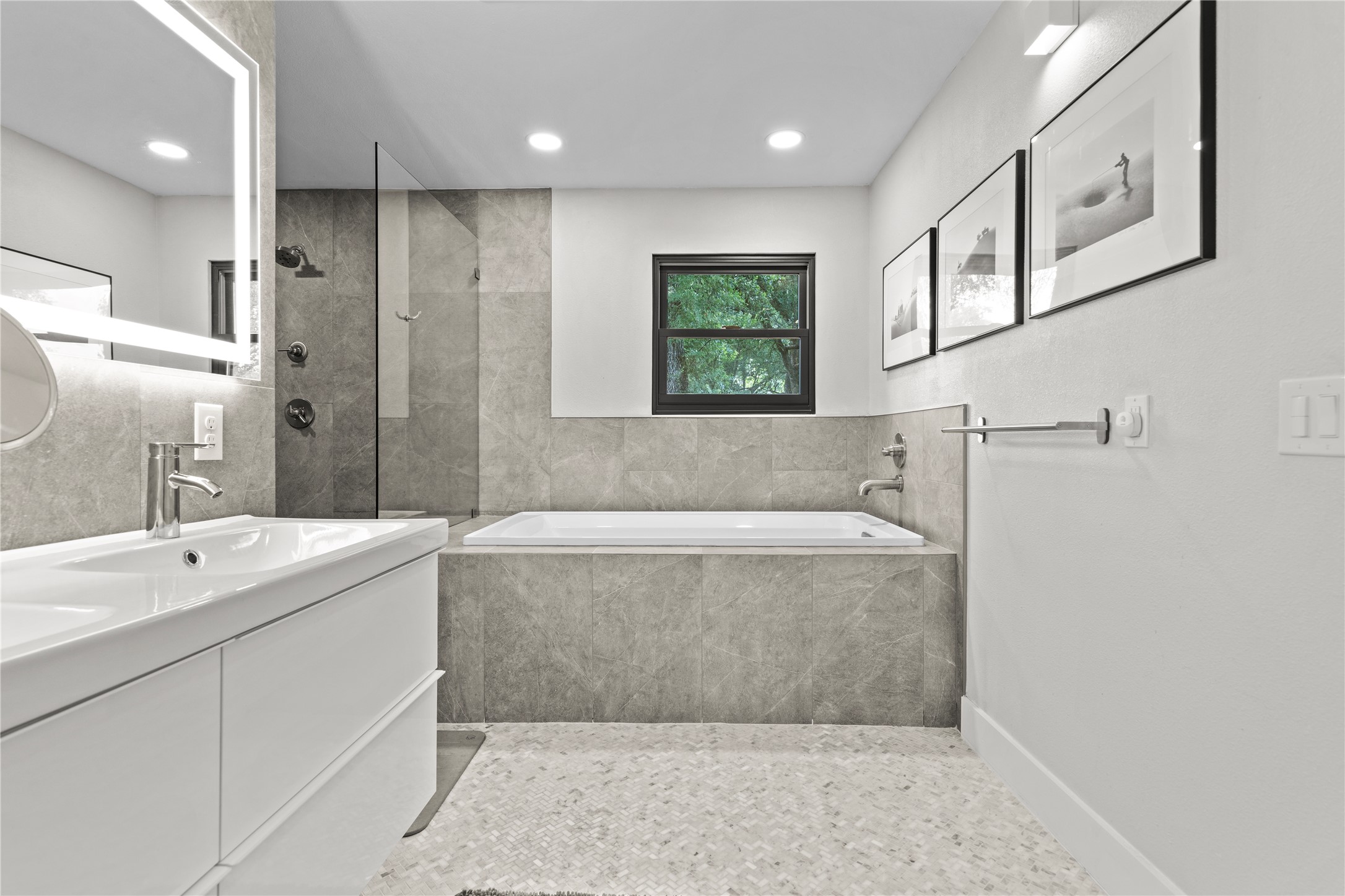 7107 Greenock Street Austin, TX 78749 - Photo 23 of 40 Bathroom featuring a white vanity with an integrated sink, a rectangular illuminated mirror, a glass-enclosed shower, a built-in bathtub, and a window