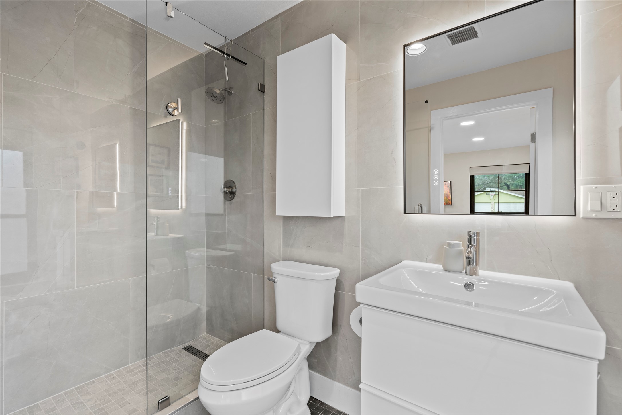 7107 Greenock Street Austin, TX 78749 - Photo 28 of 40 The bathroom features light-colored tile walls, a glass-enclosed shower, and a modern vanity with an illuminated mirror