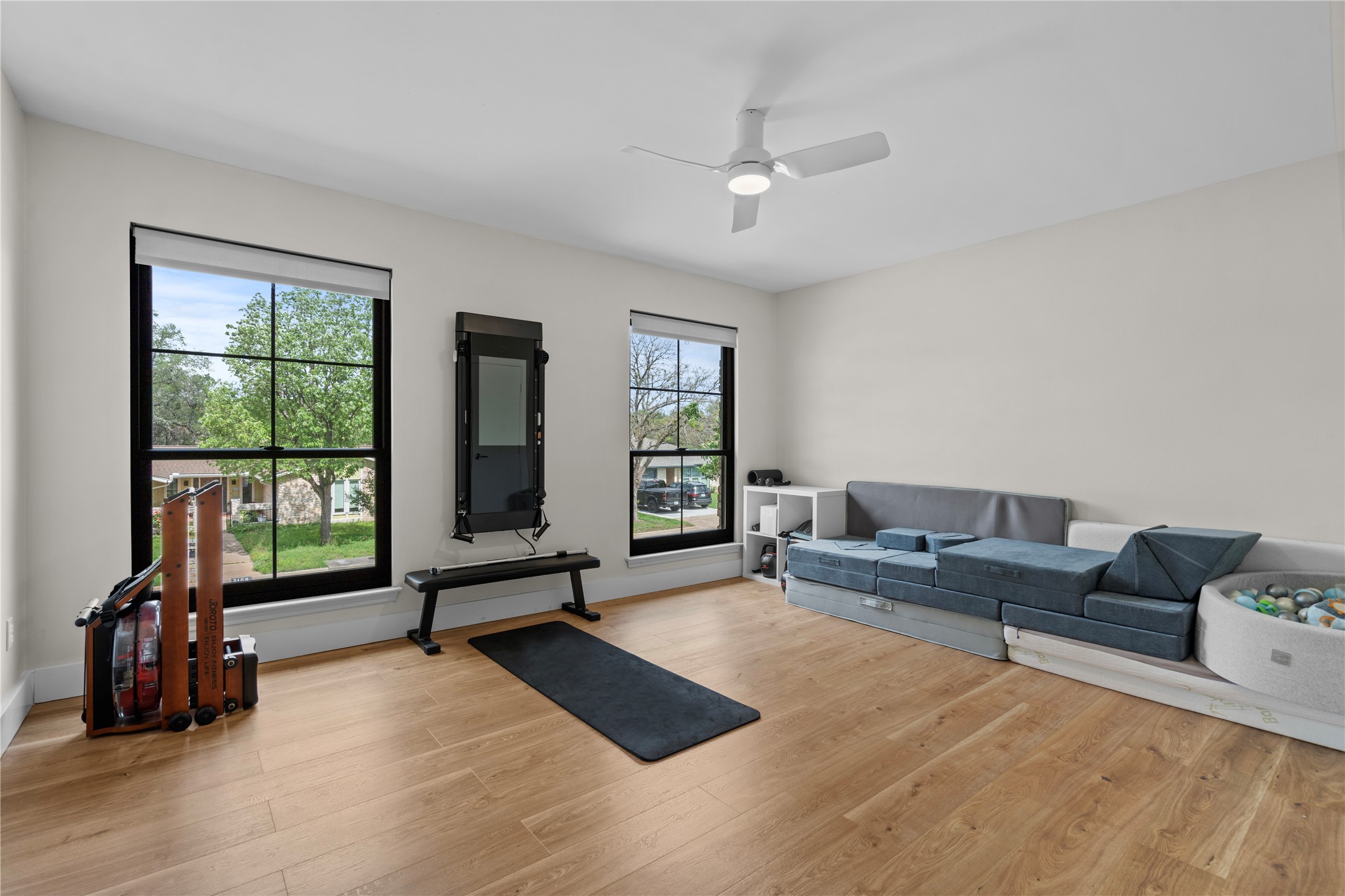7107 Greenock Street Austin, TX 78749 - Photo 30 of 40 This bright room features light hardwood floors, two large windows with black frames, and a ceiling fan