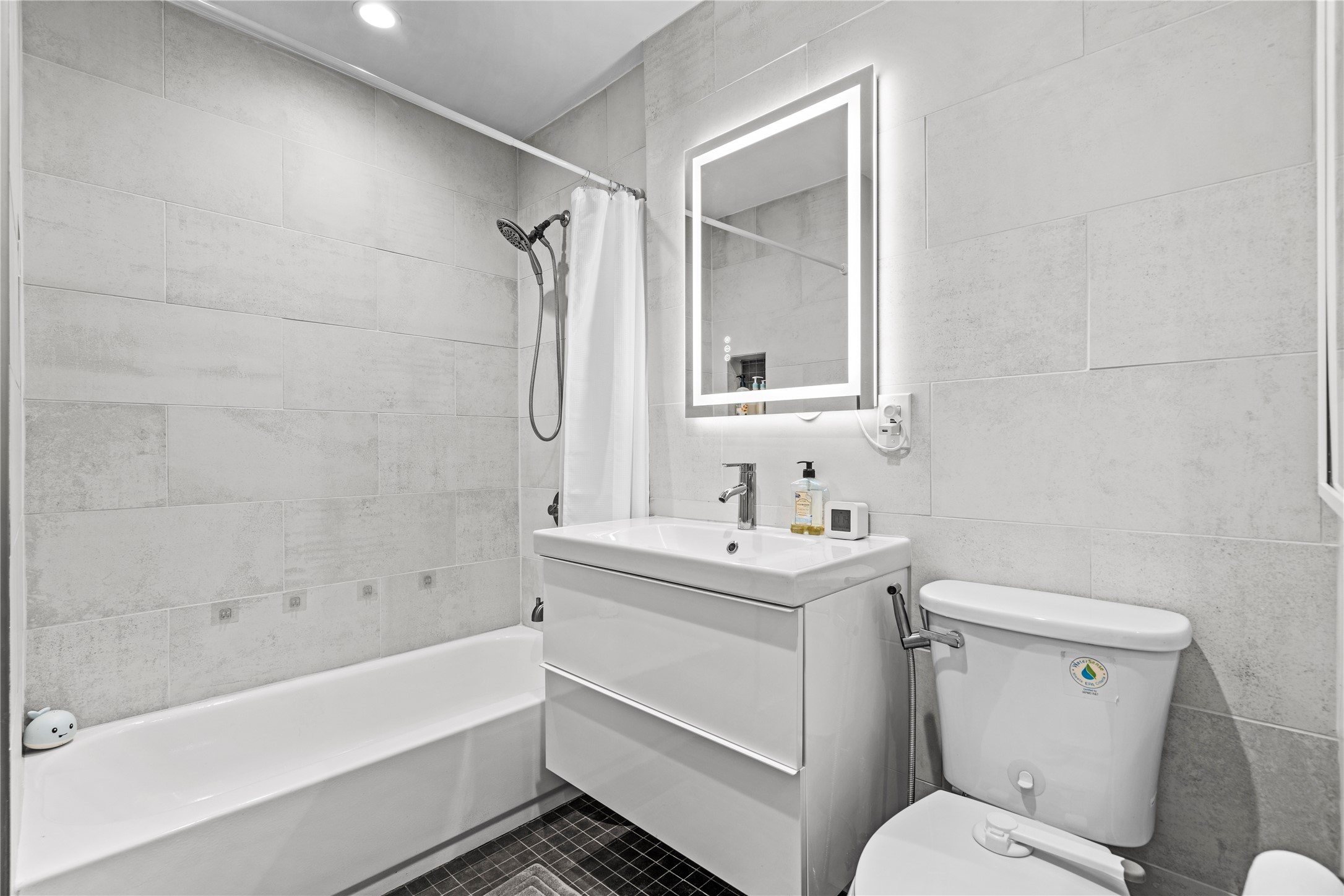 7107 Greenock Street Austin, TX 78749 - Photo 32 of 40 Bathroom featuring a modern vanity with an integrated sink, an illuminated mirror, and a tiled shower with a bathtub