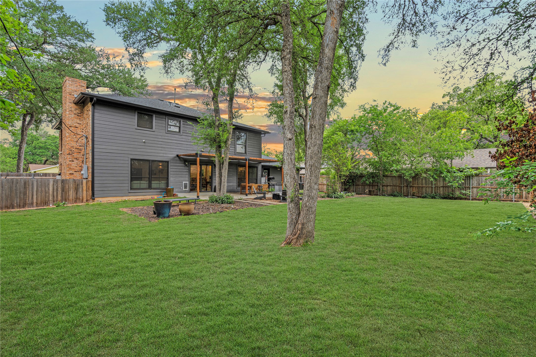 7107 Greenock Street Austin, TX 78749 - Photo 38 of 40 The property features an extensive green lawn, mature trees, and a wooden fence