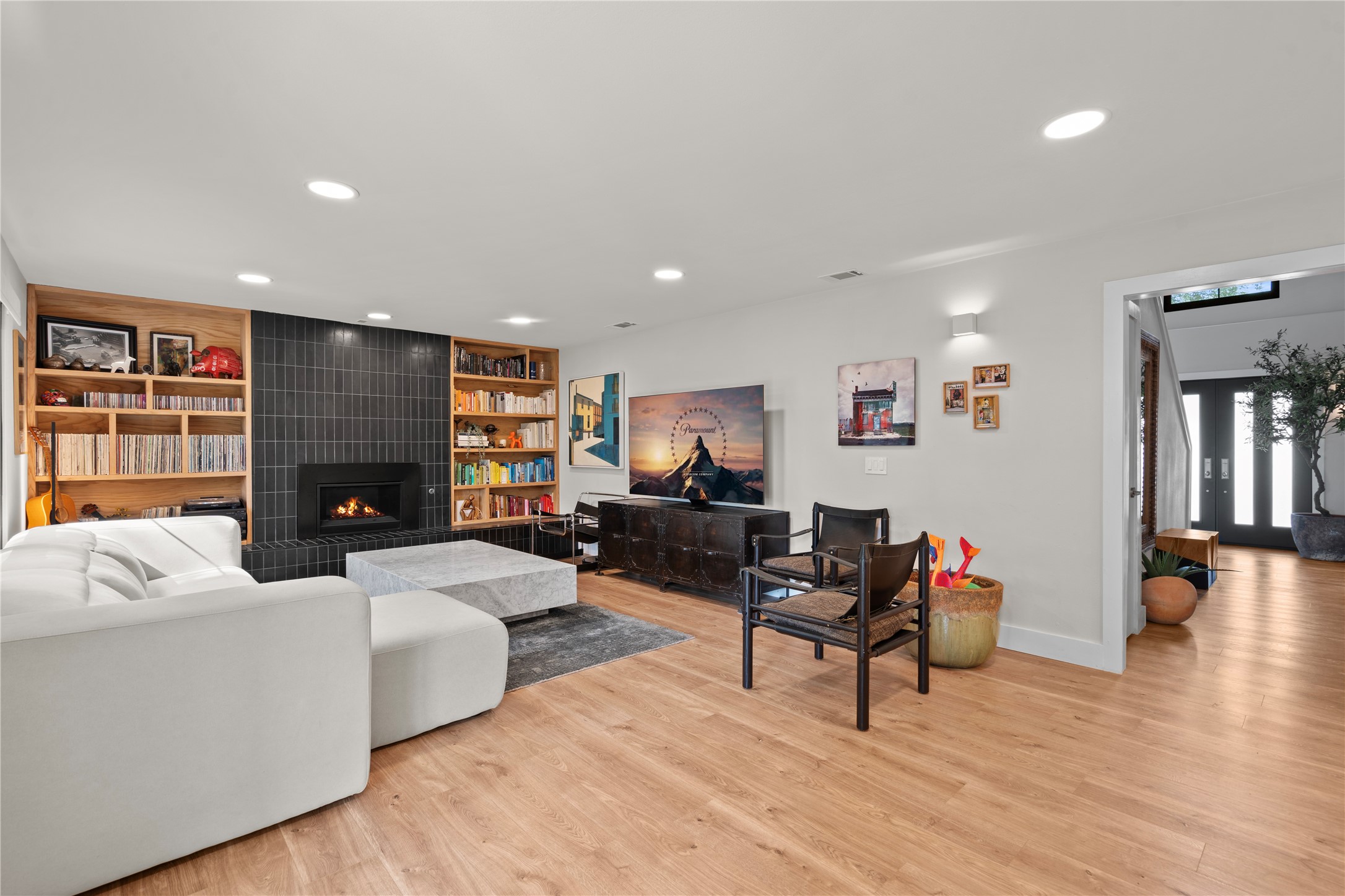 7107 Greenock Street Austin, TX 78749 - Photo 4 of 40 Living room featuring hardwood flooring, a fireplace with dark tile surround, recessed lighting, and built-in shelving