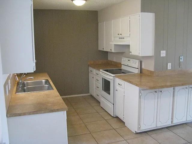 4004 Vicky Street Big Spring, TX 79720 - Photo 2 of 13 Kitchen featuring white cabinetry, light countertops, dual basin stainless steel sink, and tile flooring