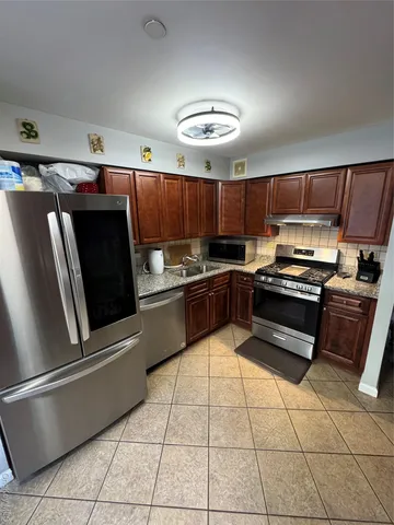a kitchen with stainless steel appliances granite countertop a refrigerator and a stove top oven