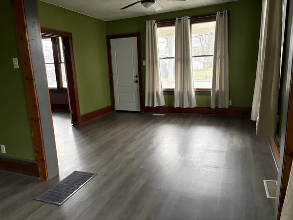 an empty room with wooden floor and windows