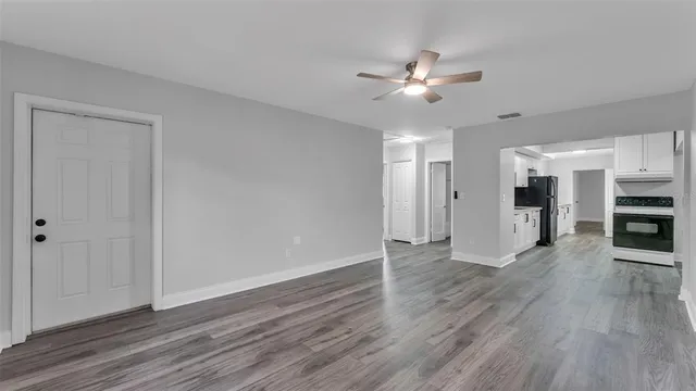 a view of a livingroom with a ceiling fan wooden floor and window