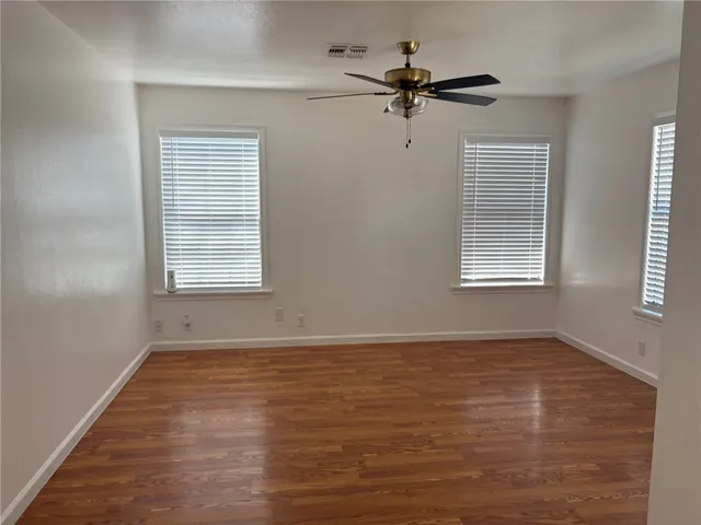 a view of an empty room with a window and wooden floor
