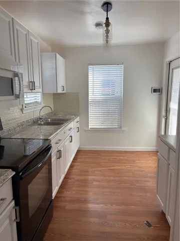 a large kitchen with granite countertop a stove sink and cabinets