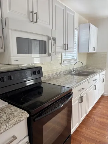 a kitchen with granite countertop a stove microwave and sink