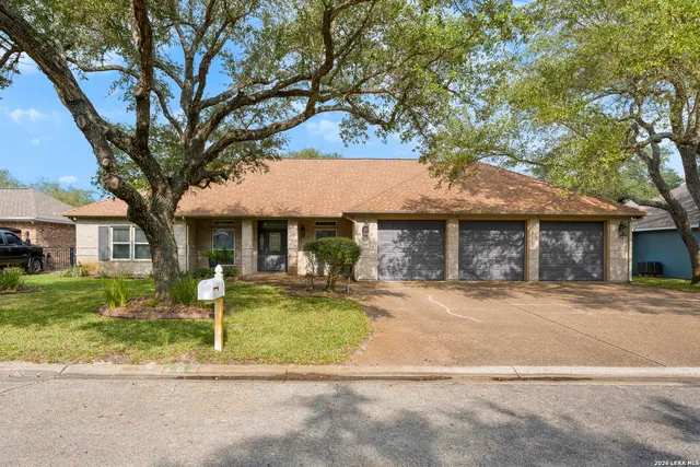 a front view of a house with garden and trees
