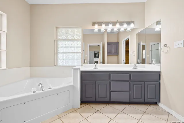 a bathroom with a double vanity sink mirror and bathtub